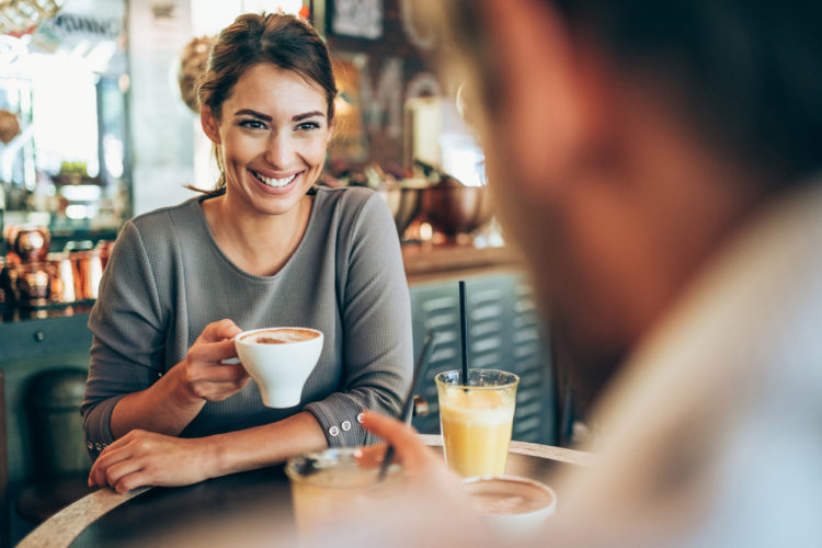 Adorable young couple drinking coffee together in city cafe.