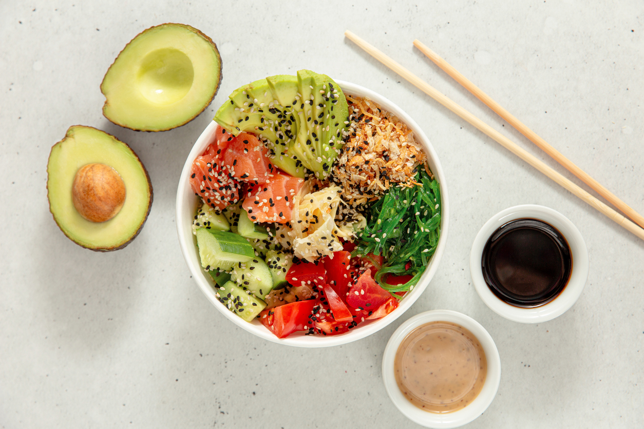 Poke bowl with salmon, avocado, cucumber, tomato and seaweed. Top view