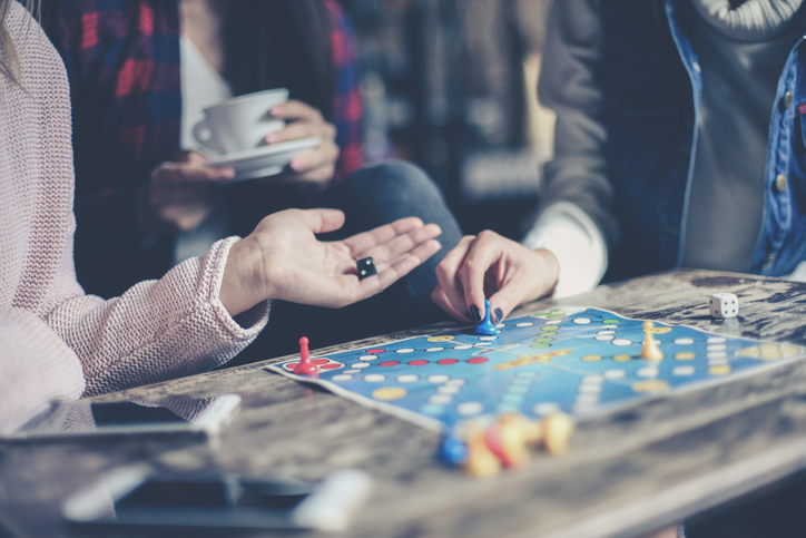 Three girls play together a social game. Focus on hand.