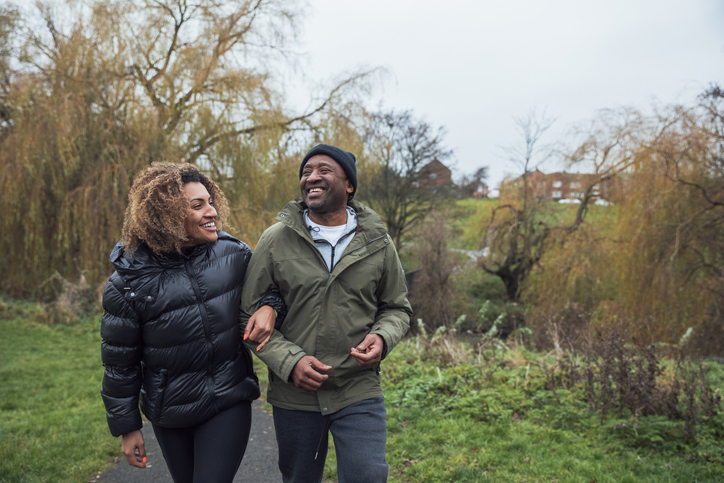 couple in winter clothing walking on a paved trail at a park