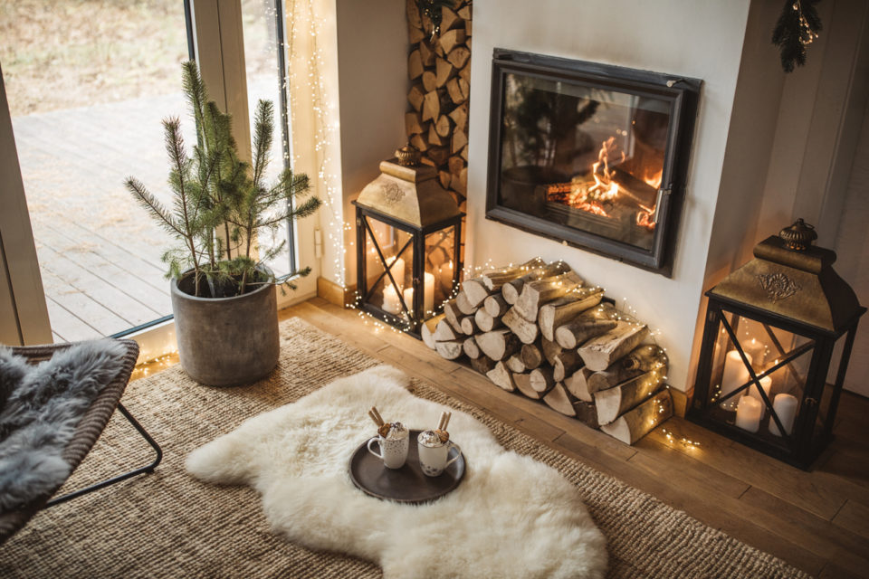 Cozy living room winter interior with fireplace, two cups with hot chocolate waiting to be drunk.