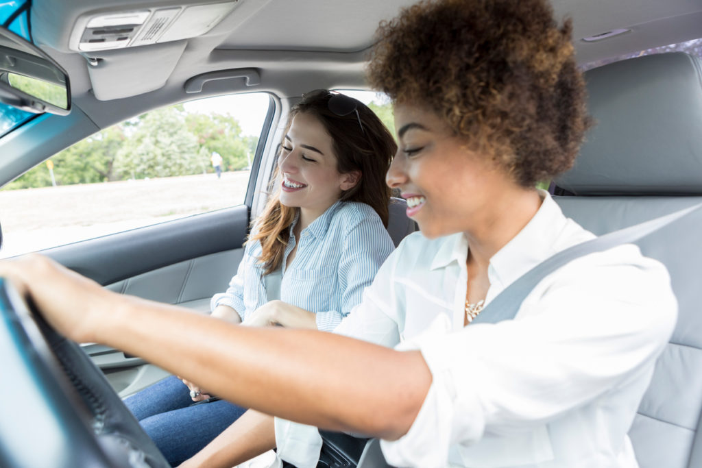 Two women sit in the front seat of car.