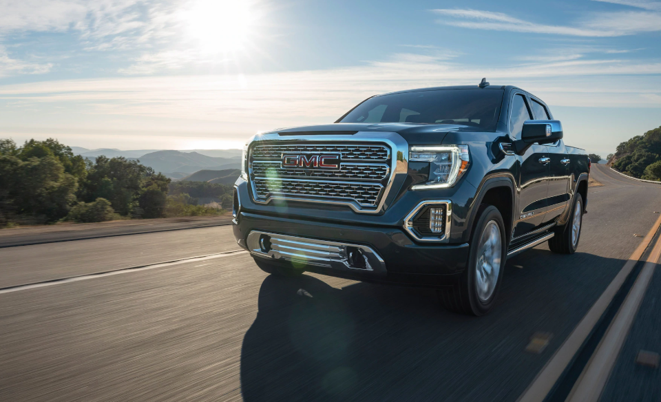 A 2020 GMC Sierra driving down the road in the sunshine.