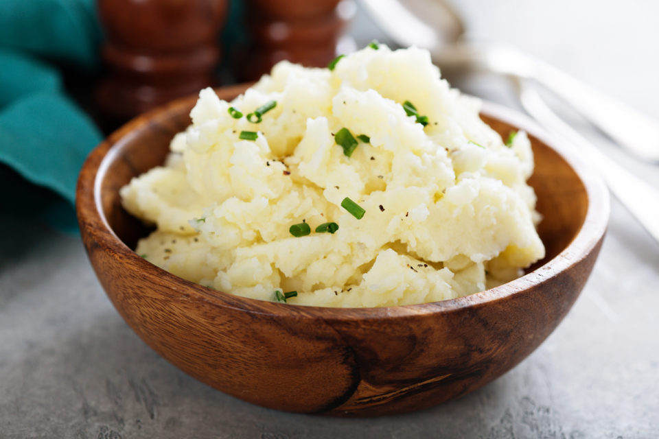 Fluffy mashed potatoes with chives in a wooden bowl