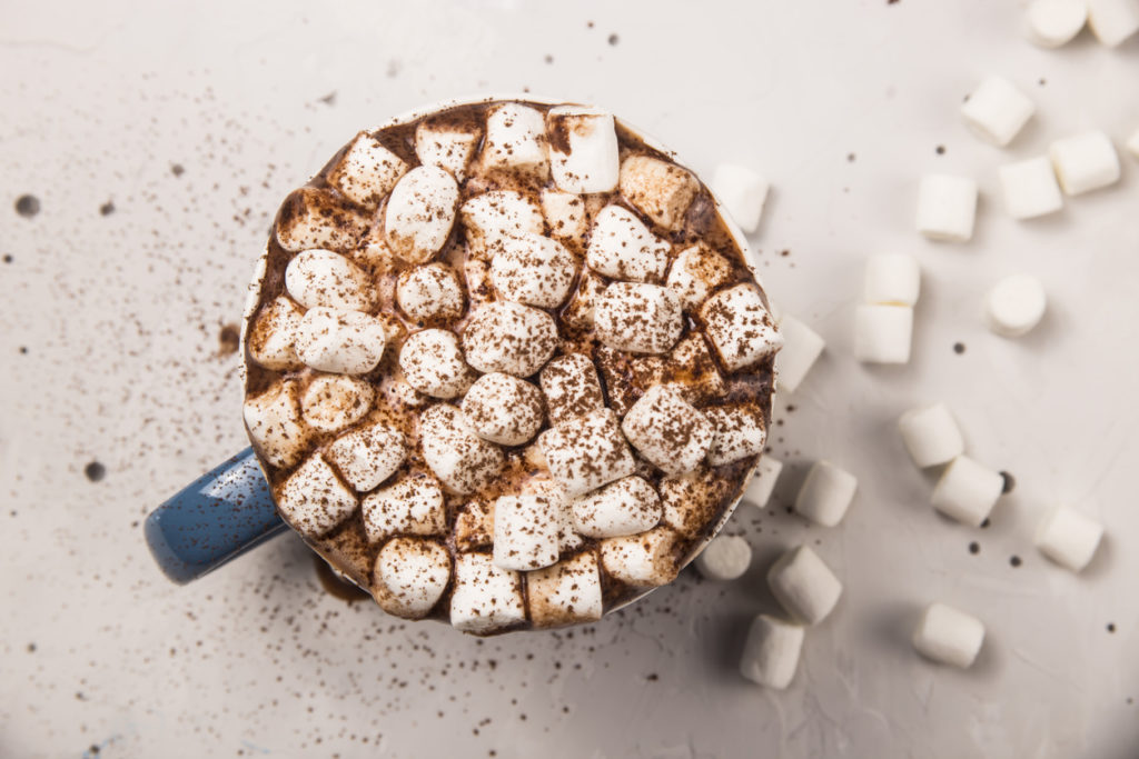 Marshmallow in a cup of hot chocolate or cocoa on a gray table.