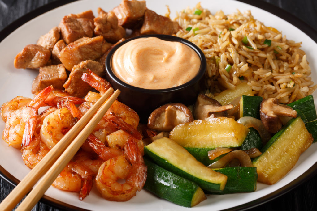 Hibachi dish consisting of fried rice with egg, shrimp, steak, and vegetables served with sauce