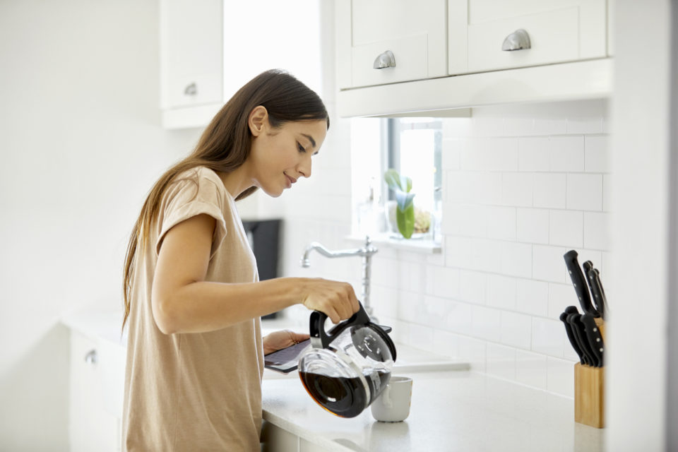 Side view of young woman pouring coffee in cup.