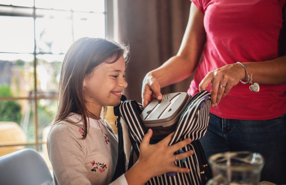 Mother preparing healthy snacks lunch boxes for daughter
