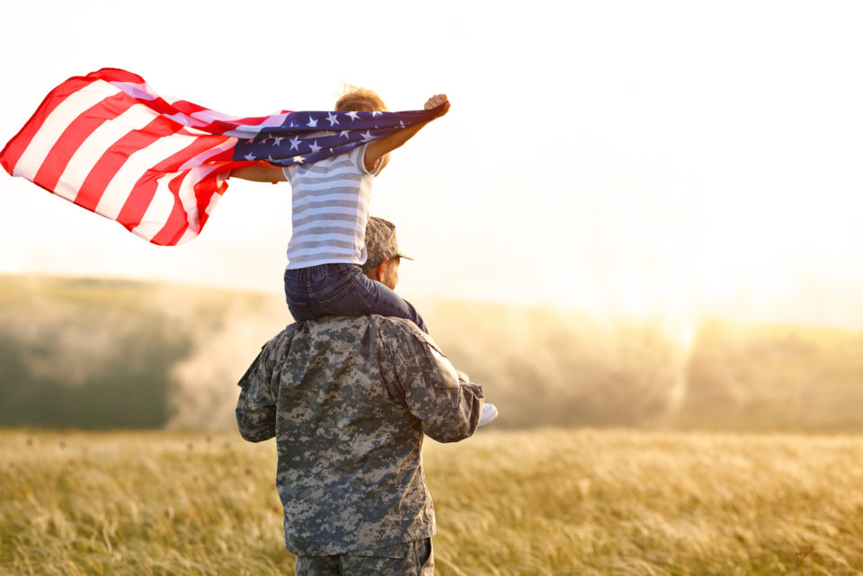 soldier and child walking through a field with American flag on Memorial day