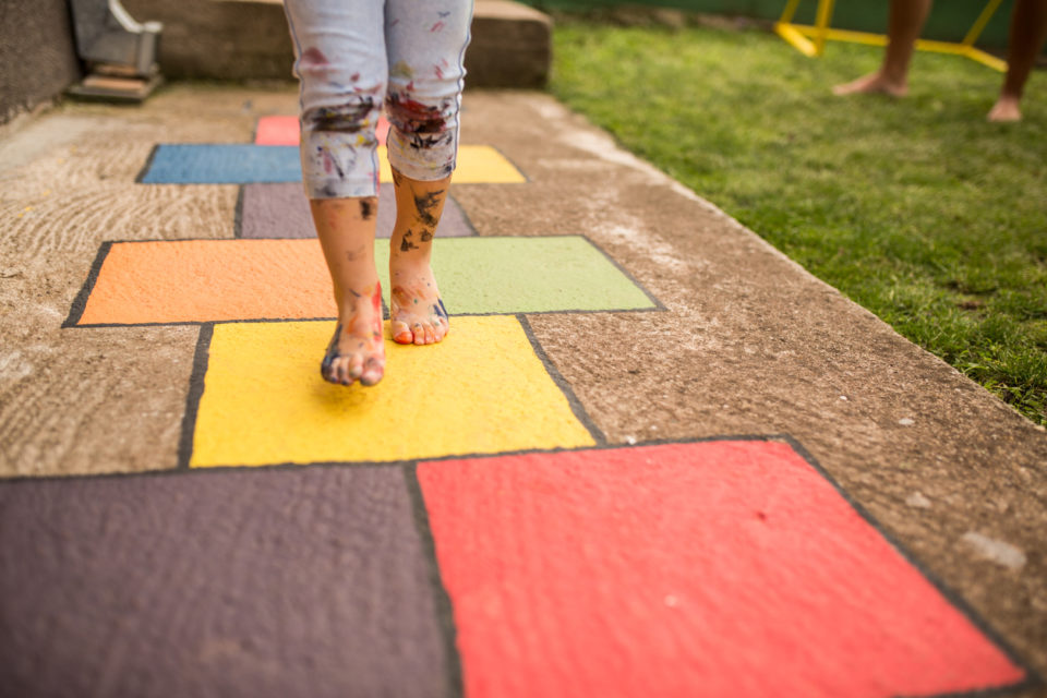 child playing hopscotch on sidewalk colored with chalk or paint