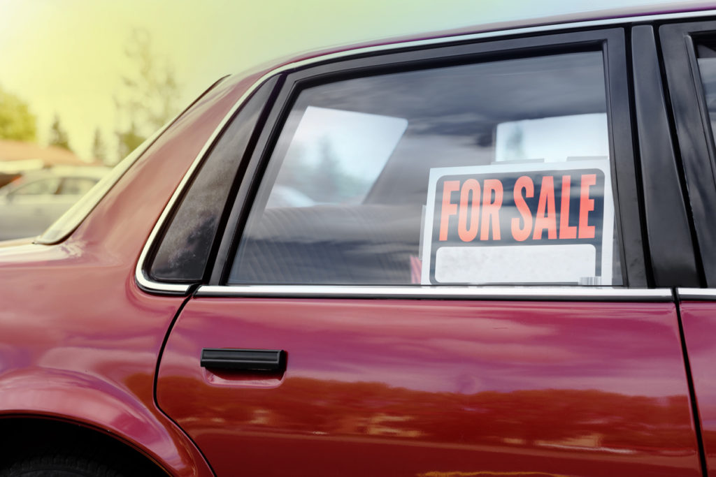 For sale sign in the rear window of a burgundy vehicle.